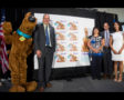 SCOOBY-DOO! Everyone’s Favorite Great Dane is now on a U.S. Postal Service Forever Stamp. L to R:-Scooby-Doo-Gary C. Reblin, VP, Product Innovation, USPS.-Cheryl Reko, USPS.-Josh Hackbarth, VP, Franchise Management and Marketing, Warner Bros. Consu